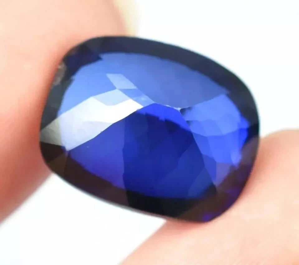 Ceylon Blue Sapphire gemstone held between fingers against a white background