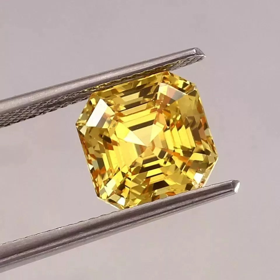 Ceylon Yellow Sapphire gemstone held by tweezers against a neutral background