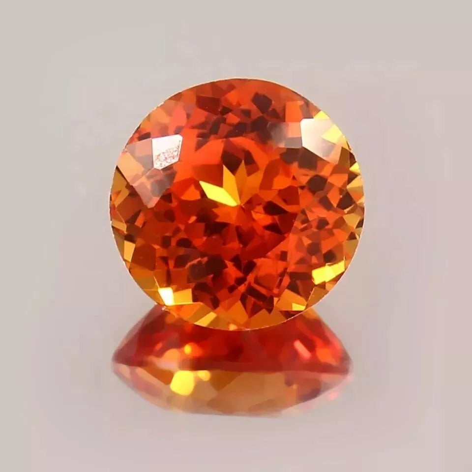 Round Orange Sapphire gemstone on a light gray background