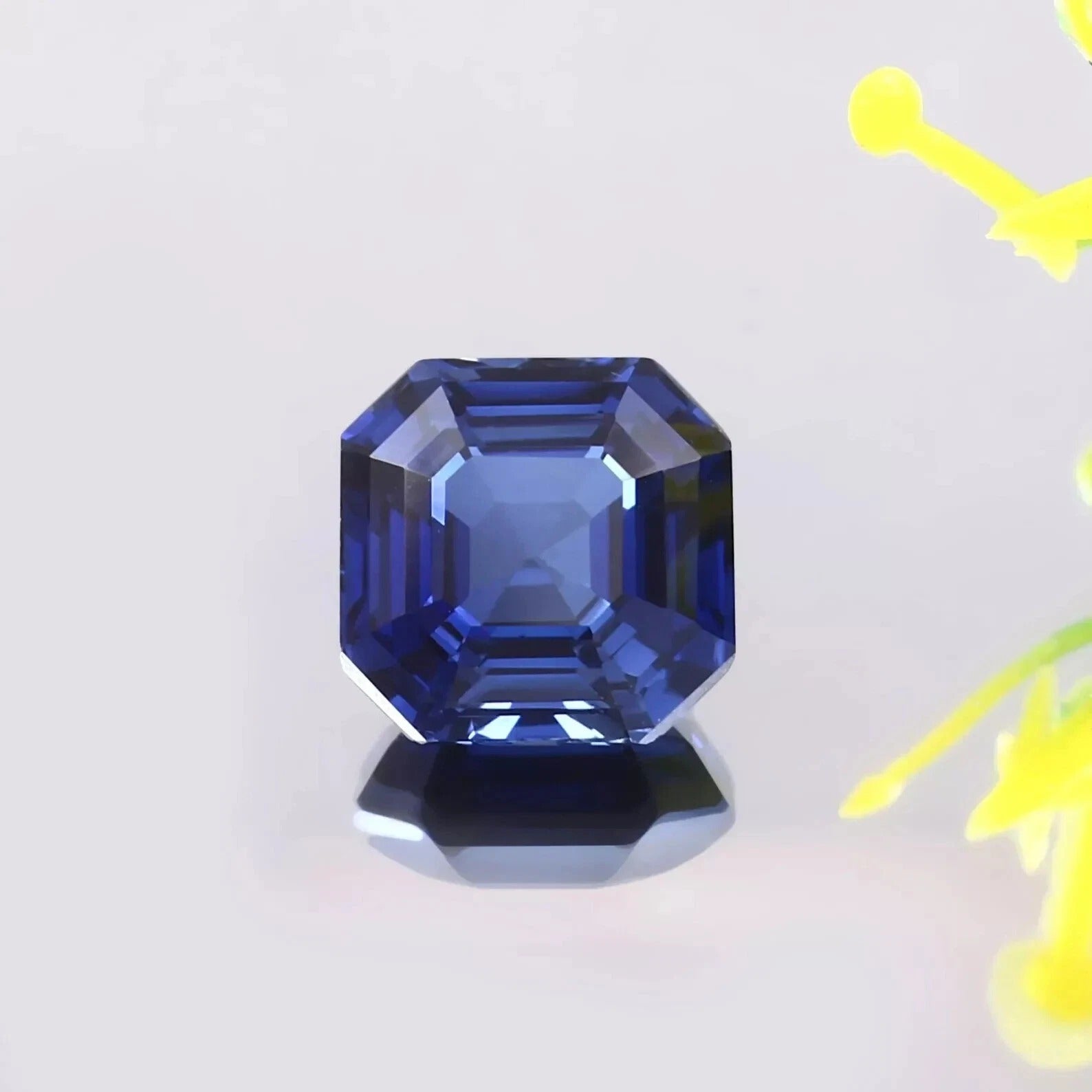 Faceted Blue Sapphire gemstone on a light gray background