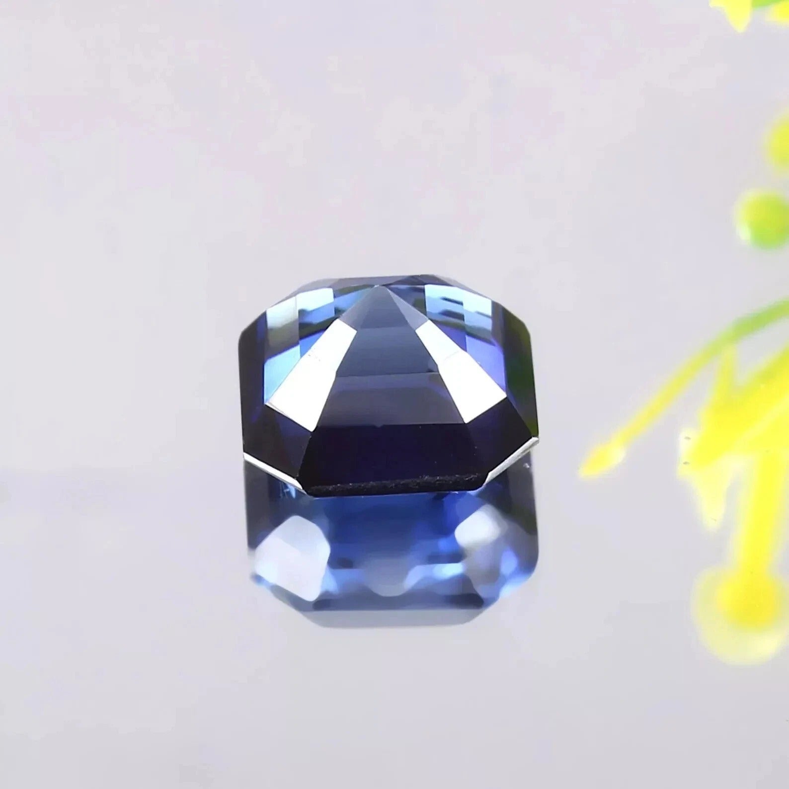 Faceted Blue Sapphire gemstone on a light gray background