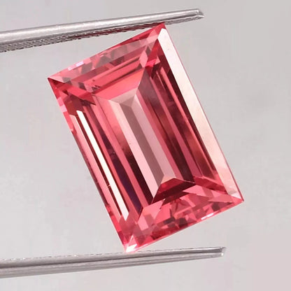 Padparadscha Sapphire – Baguette Cut gemstone held by tweezers on a light gray background