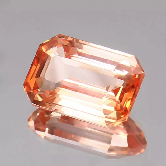 Bi-Color Padparadscha gemstone on a gray background
