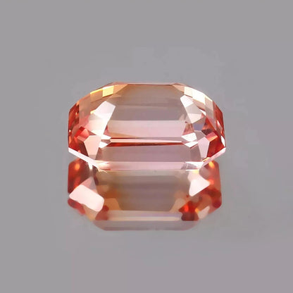 Bi-Color Unheated Padparadscha sapphire Faceted gemstone on a gray background