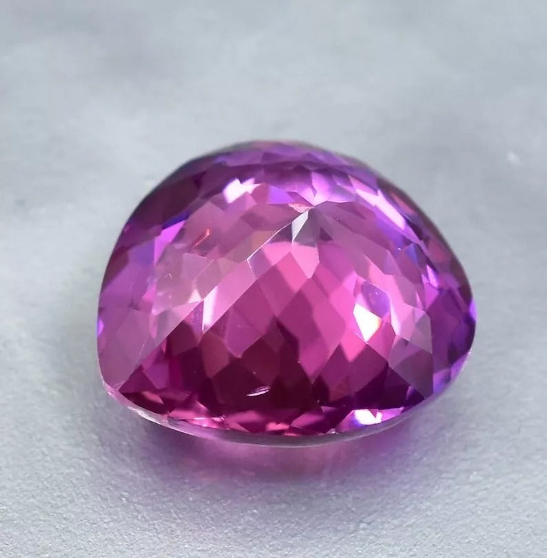 Faceted Purple Blue Sapphire gemstone on a light gray background