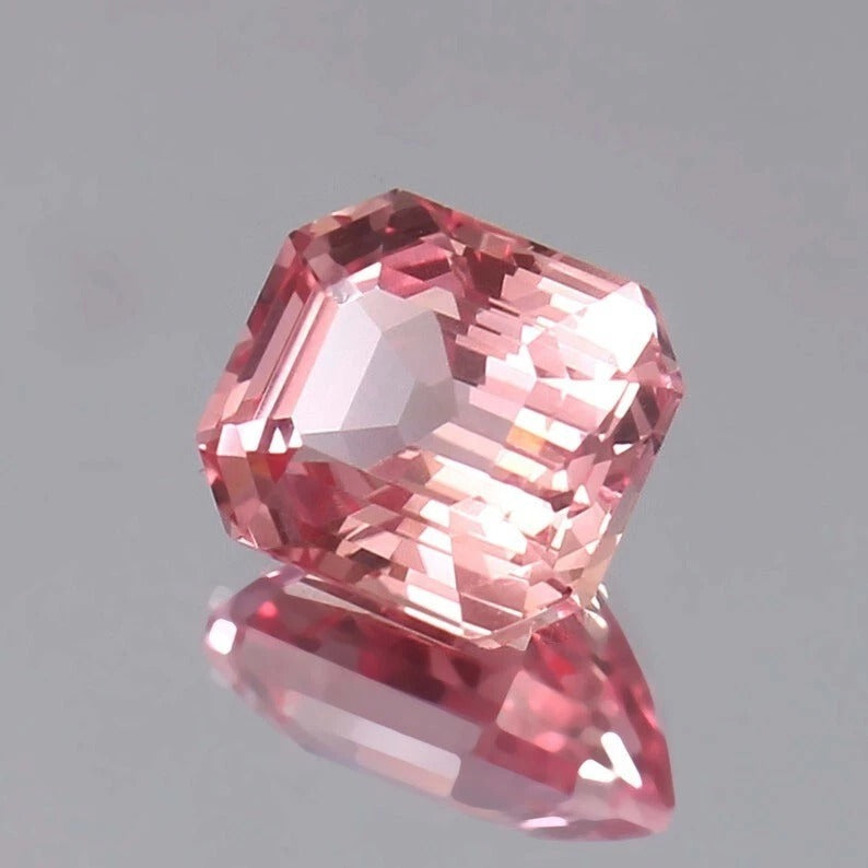 Pink Padparadscha Sapphire gemstone on a gray background