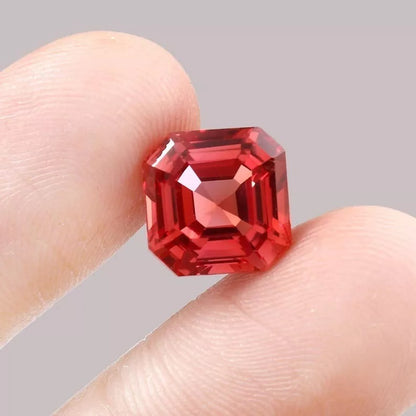 Padparadscha Sapphire gemstone held between fingers against a neutral background