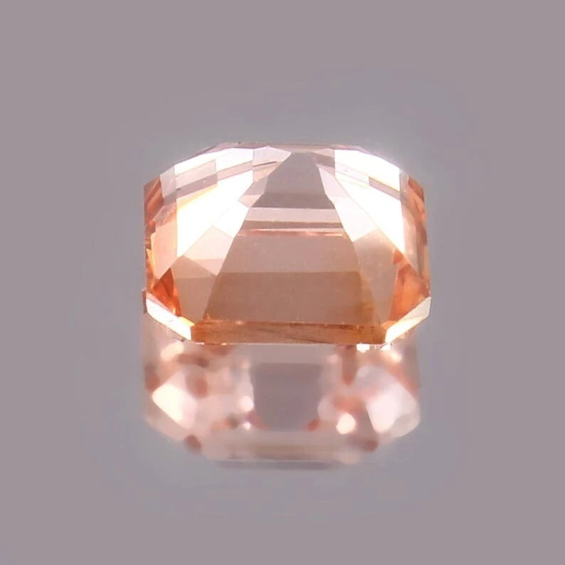 Padparadscha Sapphire – Peach Faceted gemstone on a gray background