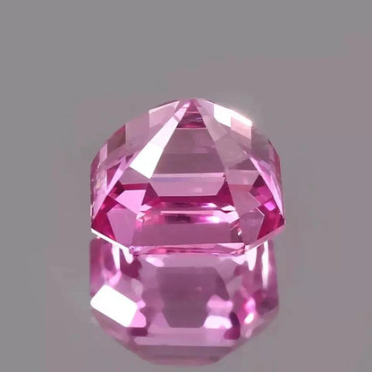 Faceted Ceylon Pink Sapphire gemstone on a gray background