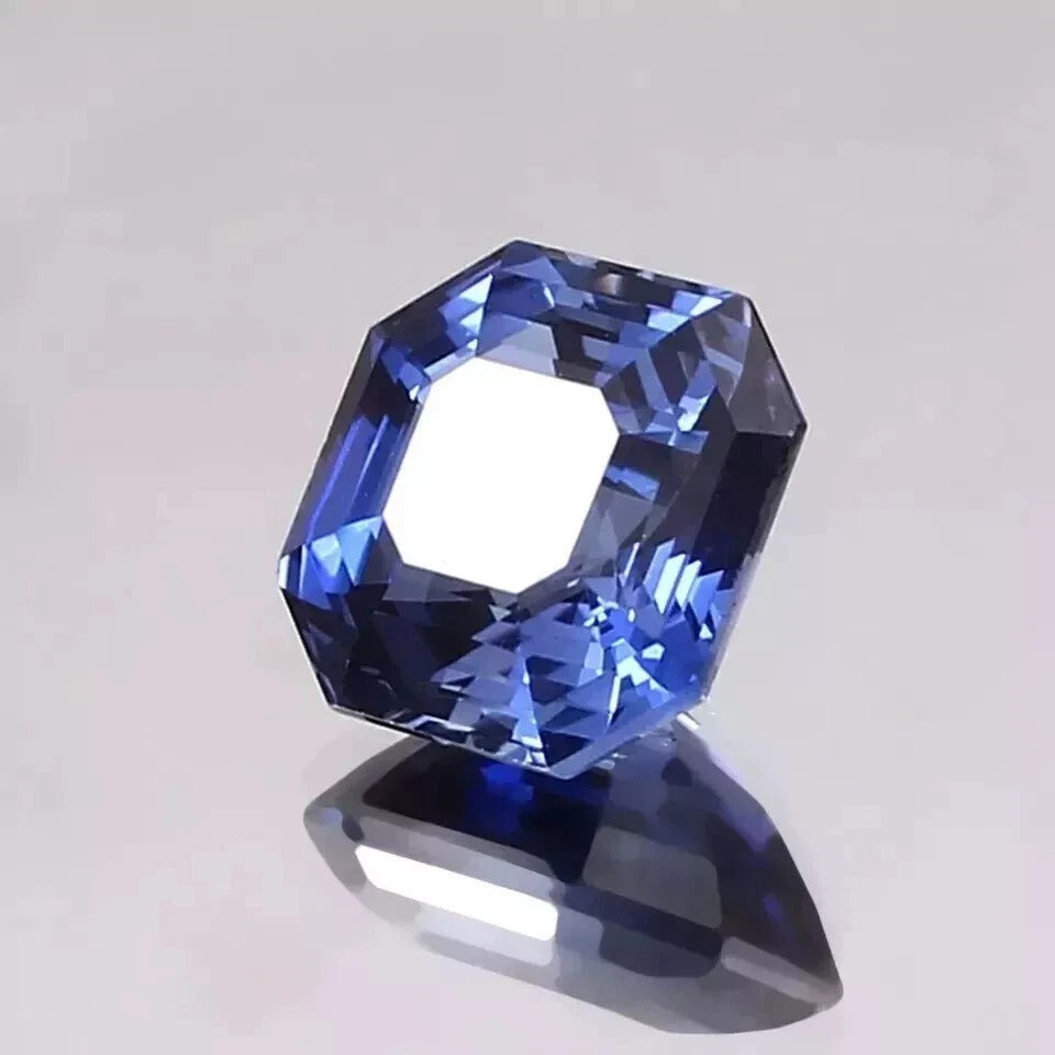 Faceted Royal Blue Sapphire gemstone on a light gray background