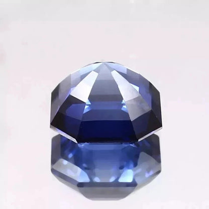 Faceted Royal Blue Sapphire gemstone on a light gray background
