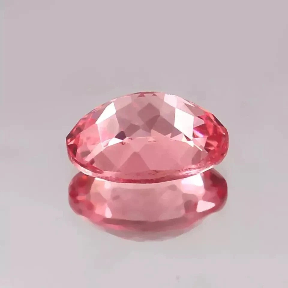 Faceted Padparadscha Sapphire Peach To Pink gemstone on a gray background