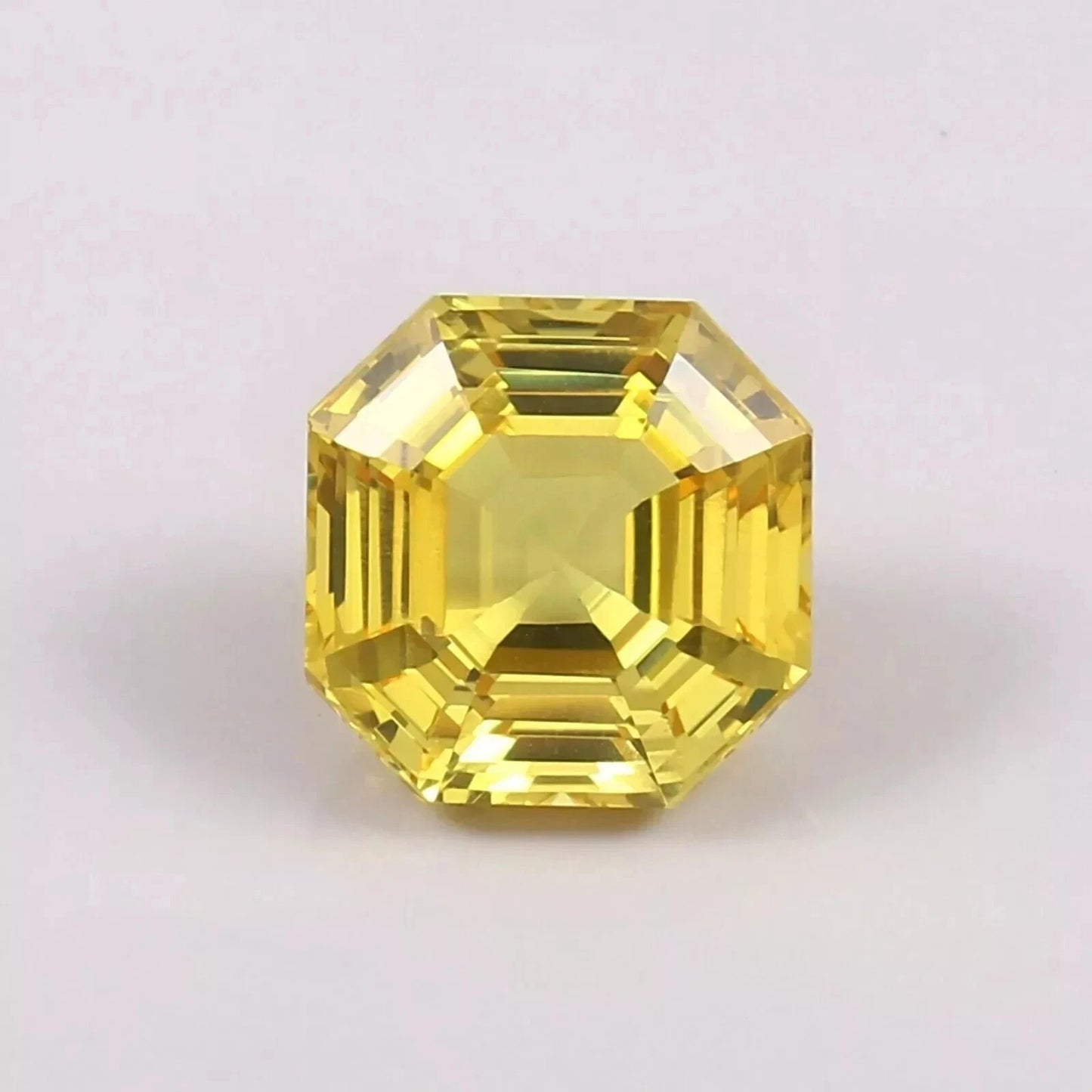 Yellow Sapphire asscher gemstone with a geometric cut on a light pink background