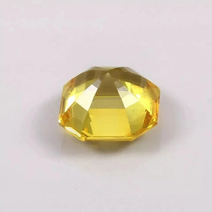 Faceted yellow Sapphire asscher gemstone on a light gray background