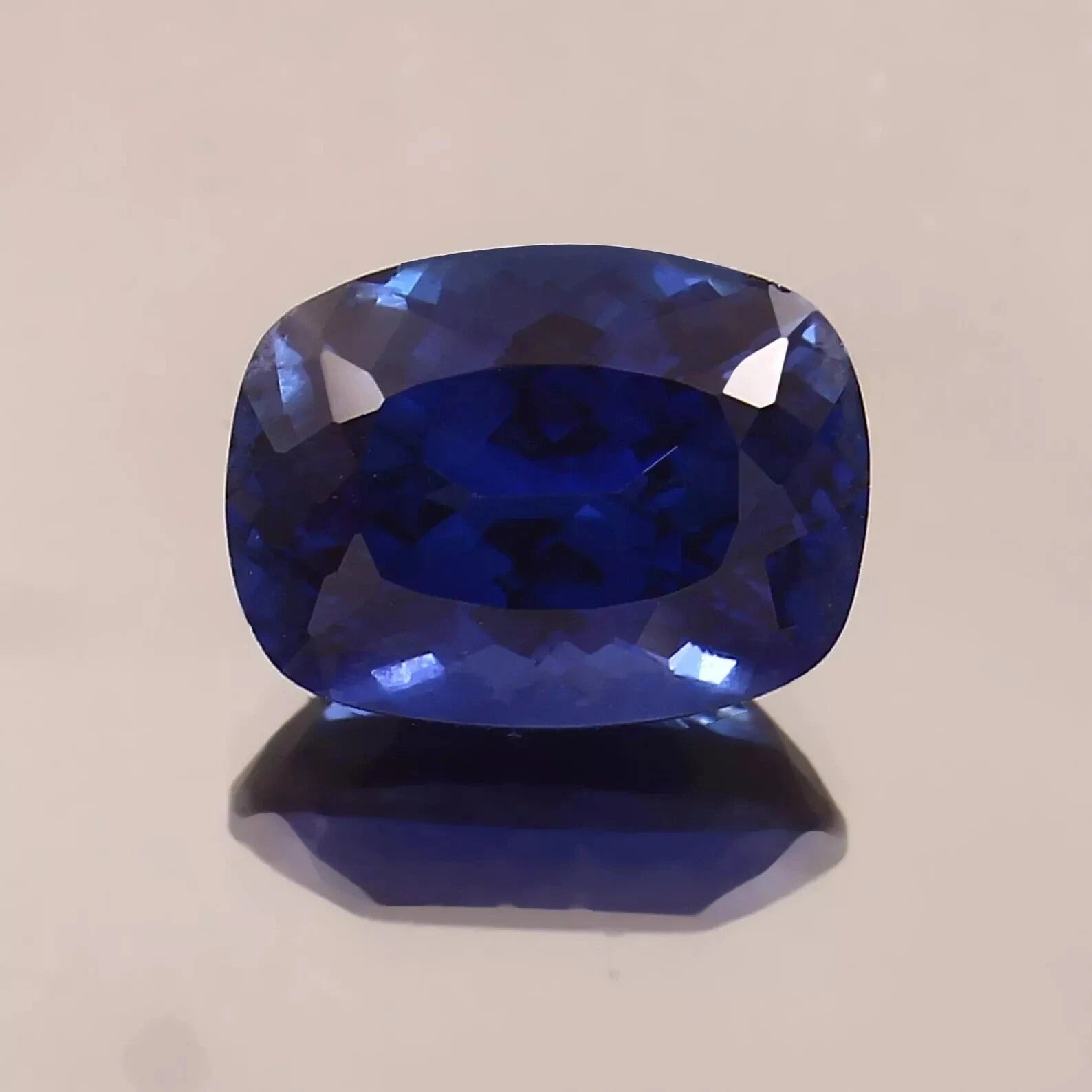 Faceted Blue Sapphire gemstone on a beige background