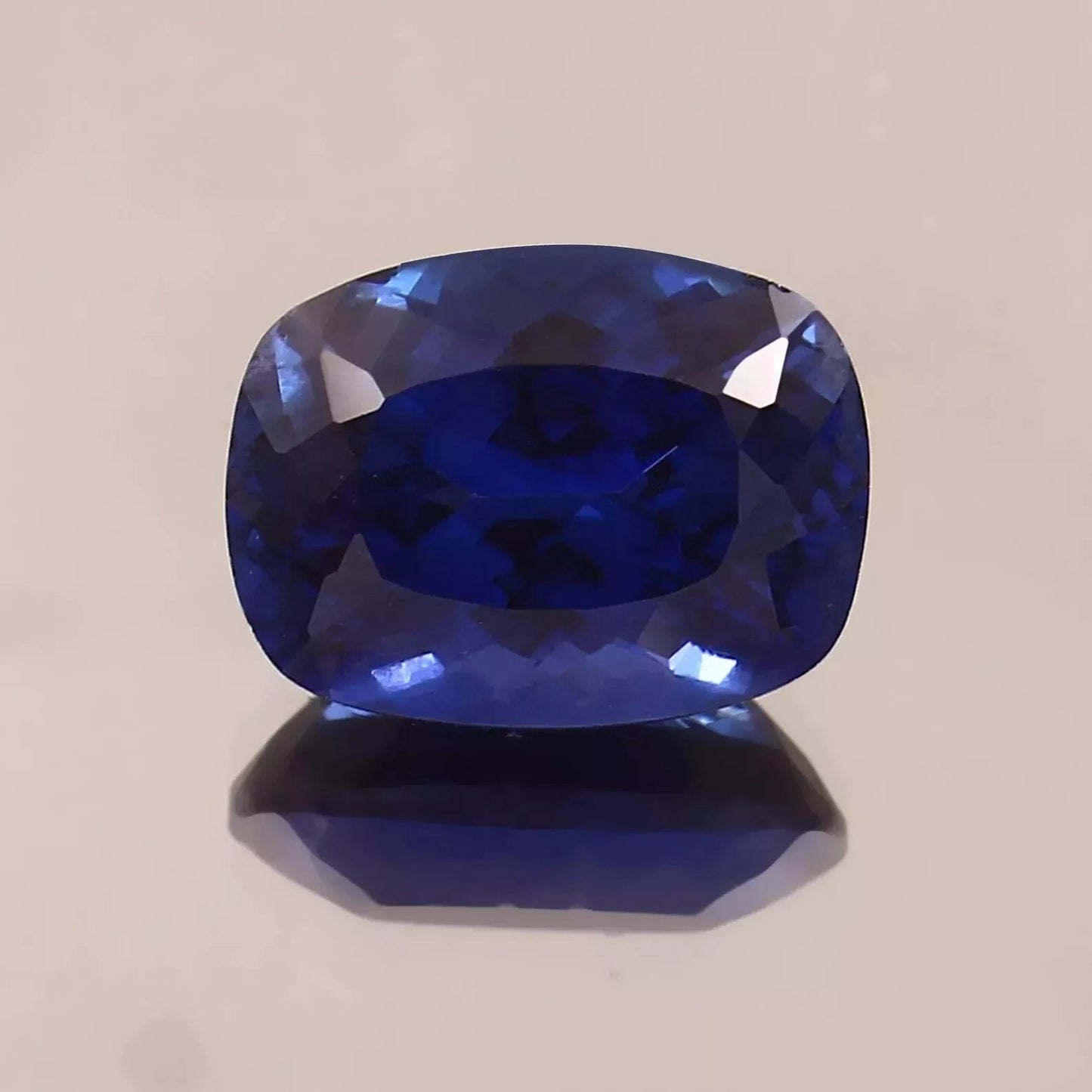 Faceted Blue Sapphire gemstone on a beige background