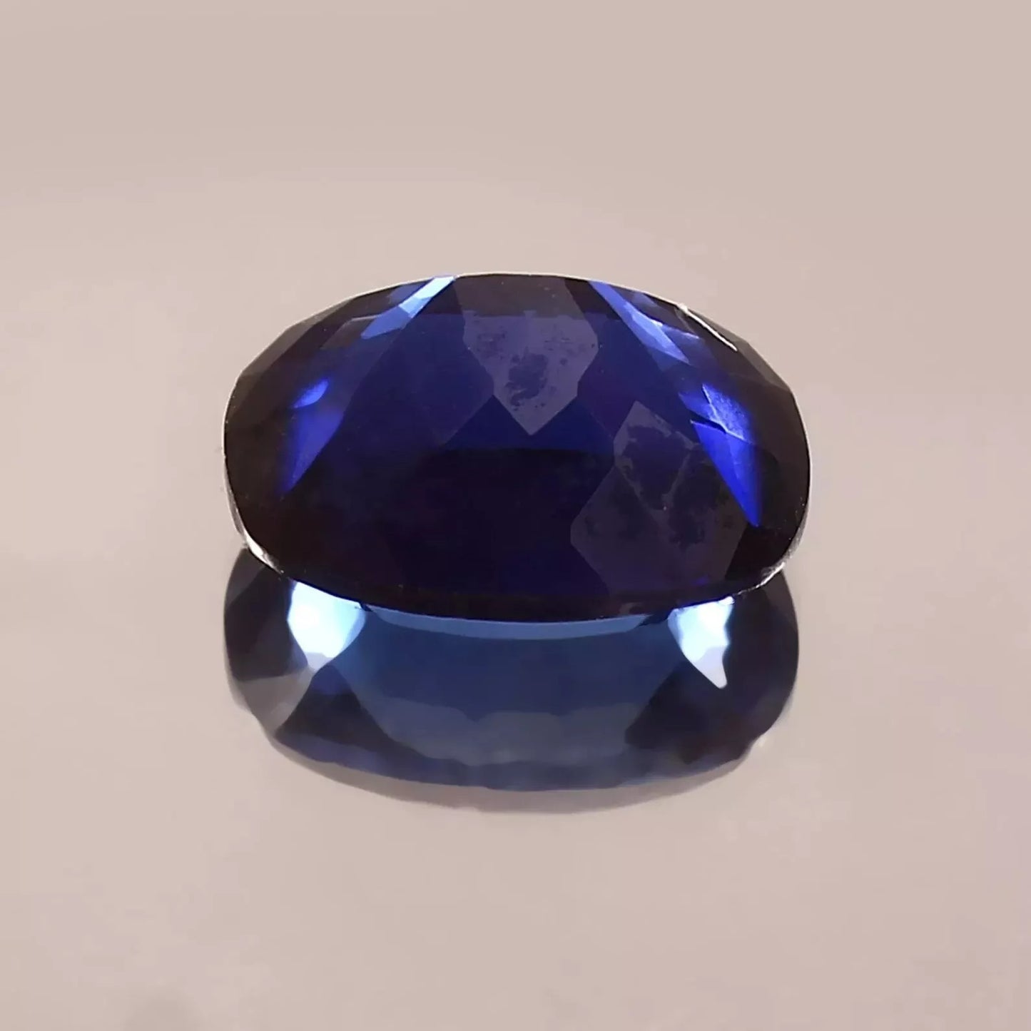Faceted Blue Sapphire gemstone on a beige background