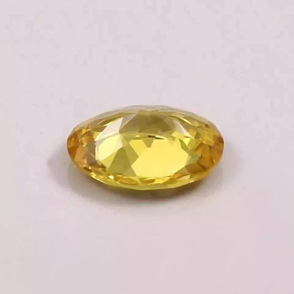 Faceted yellow sapphire gemstone on a light gray background