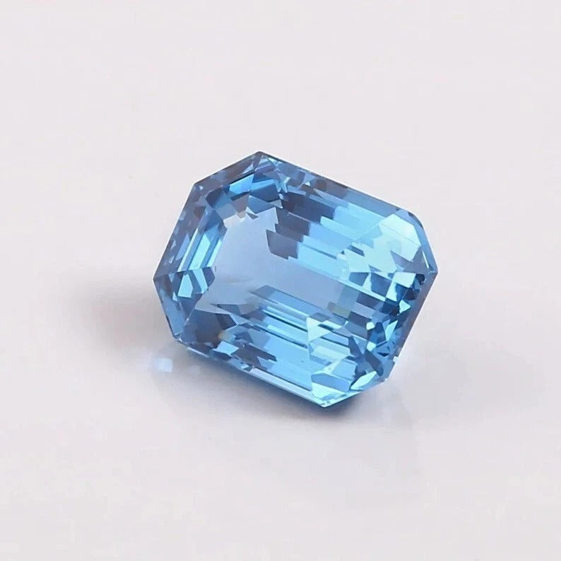 Faceted blue Aquamarine gemstone on a light gray background
