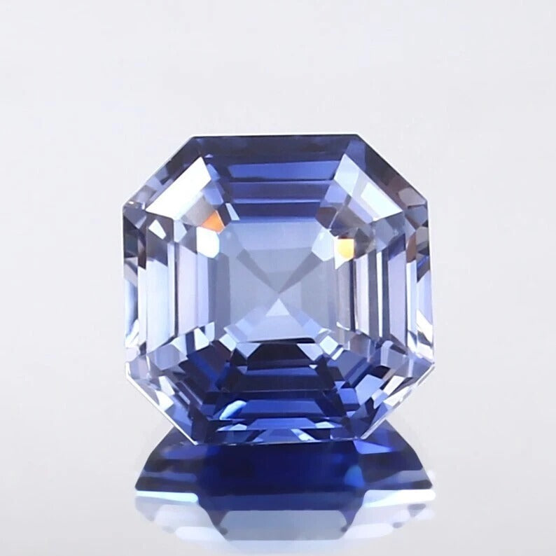 Faceted Cornflower Blue Sapphire gemstone on a light gray background