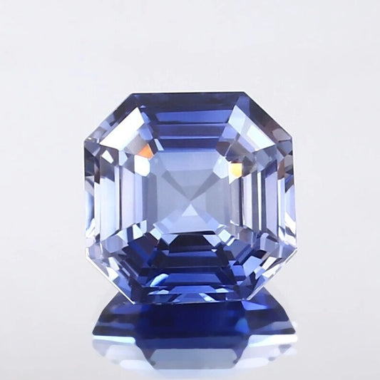 Faceted Cornflower Blue Sapphire gemstone on a light gray background