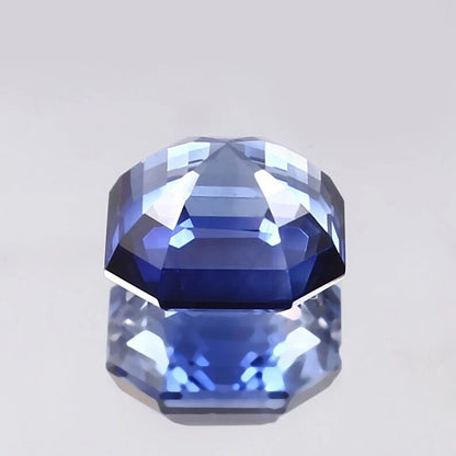 Faceted Cornflower Blue Sapphire gemstone on a light gray background