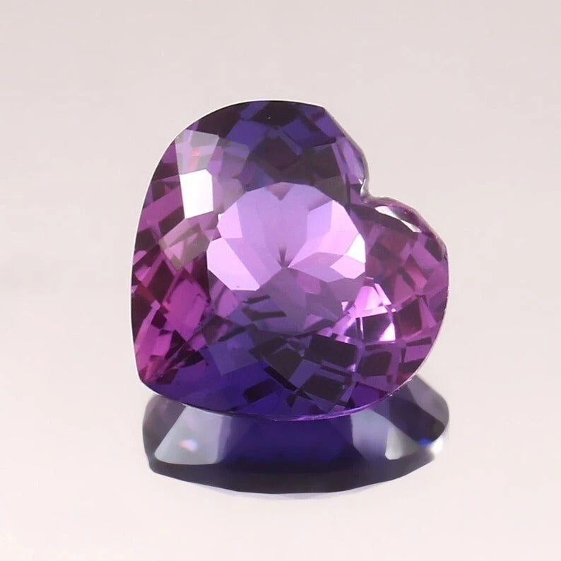 Heart-shaped Purple-Pink Sapphire gemstone on a light gray background