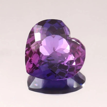 Heart-shaped Purple-Pink Sapphire gemstone on a light gray background