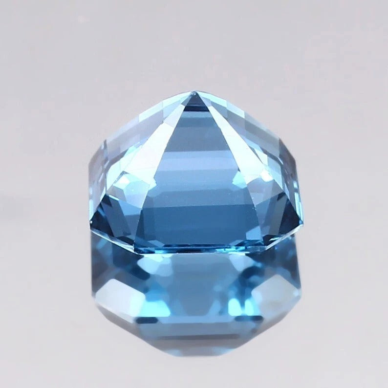 Faceted Swiss Blue Topaz gemstone on a light gray background