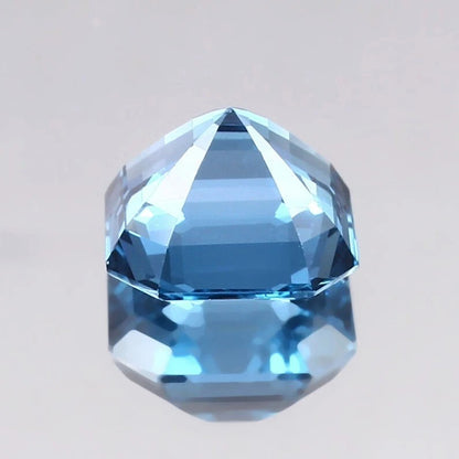 Faceted Swiss Blue Topaz gemstone on a light gray background