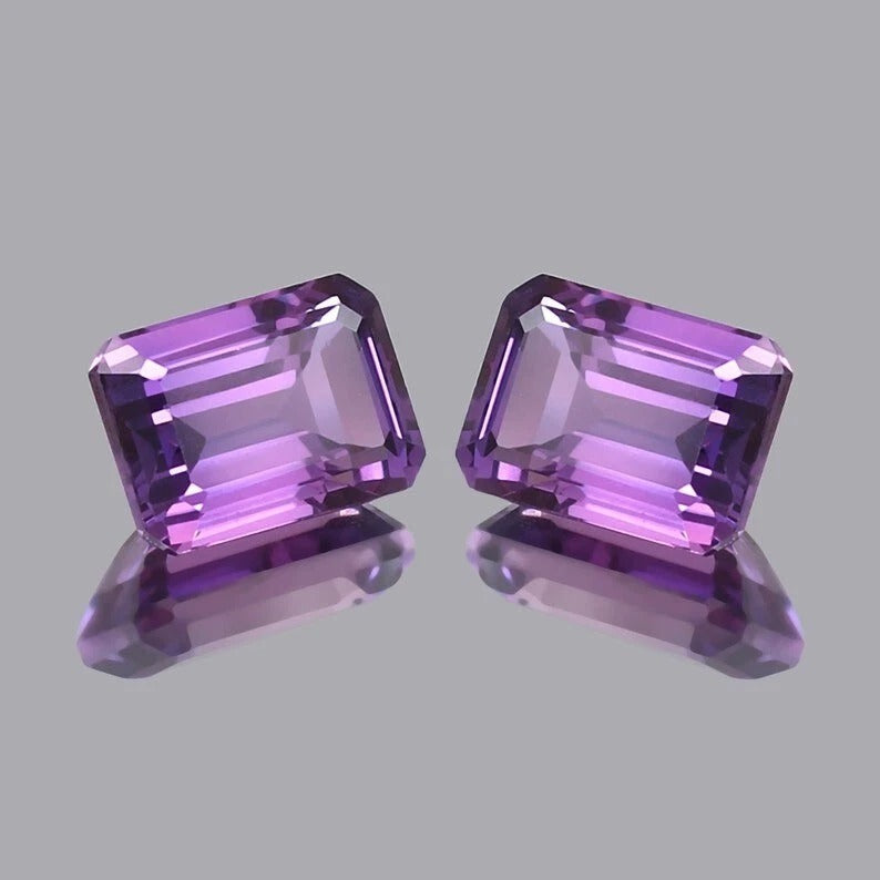 Pair Ceylon Purple Sapphire gemstones on a gray background