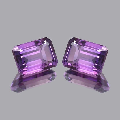 Pair Ceylon Purple Sapphire gemstones on a gray background