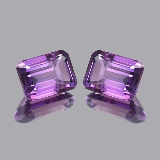 Pair Ceylon Purple Sapphire gemstones on a gray background