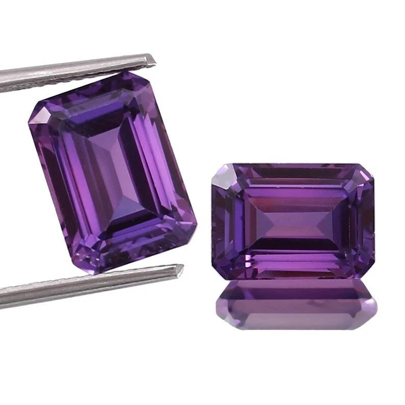 Pair Ceylon Purple Sapphire emerald-cut purple gemstones with tweezers on a white background