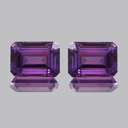 Pair Ceylon Purple Sapphire emerald-cut purple gemstones on a light gray background