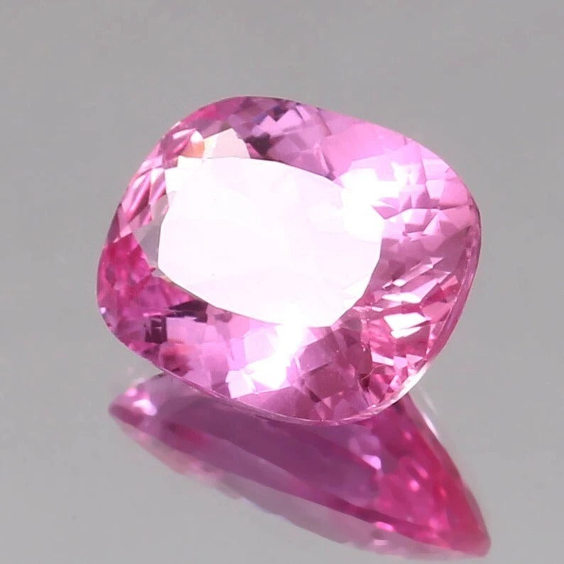 Unheated Pink Sapphire -shaped pink gemstone on a gray background