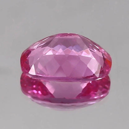 Faceted Unheated Pink Sapphire gemstone on a gray background