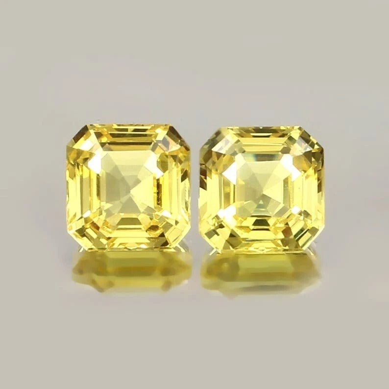Yellow Ceylon Sapphire Pair gemstones with a reflective surface on a gray background