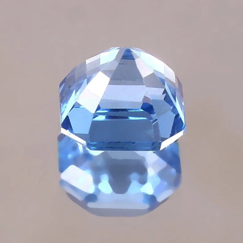 Faceted Blue Spinel gemstone on a beige background