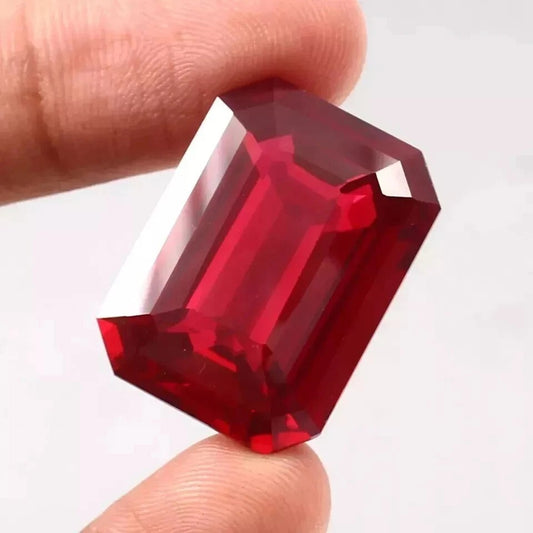 Red  Mozambique Ruby gemstone held between fingers against a white background