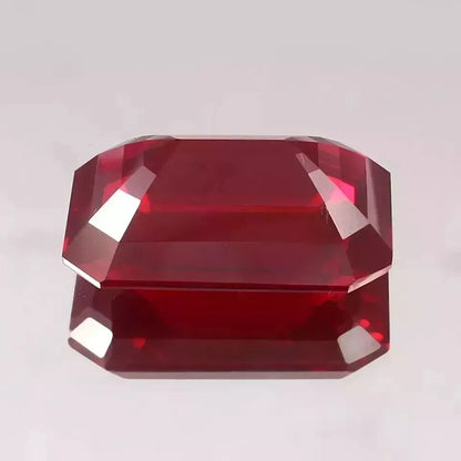 Faceted Mozambique Ruby emerald cutgemstone on a light gray background