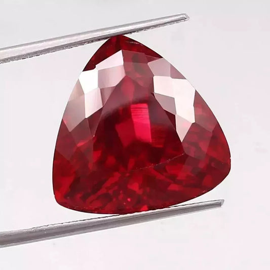 Mozambique Blood Red Ruby Trillion Cut gemstone held by tweezers on a white background