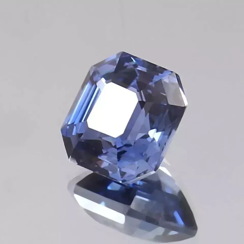 Faceted Royal Blue Sapphire gemstone on a gray background