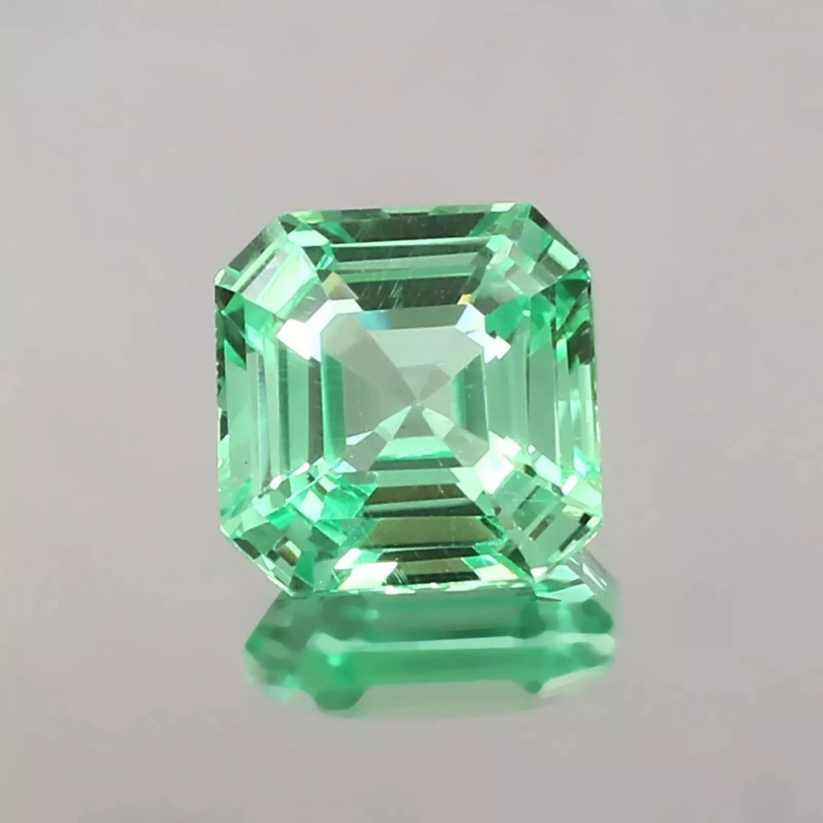 sapphire asscher cut green gemstone on a gray background