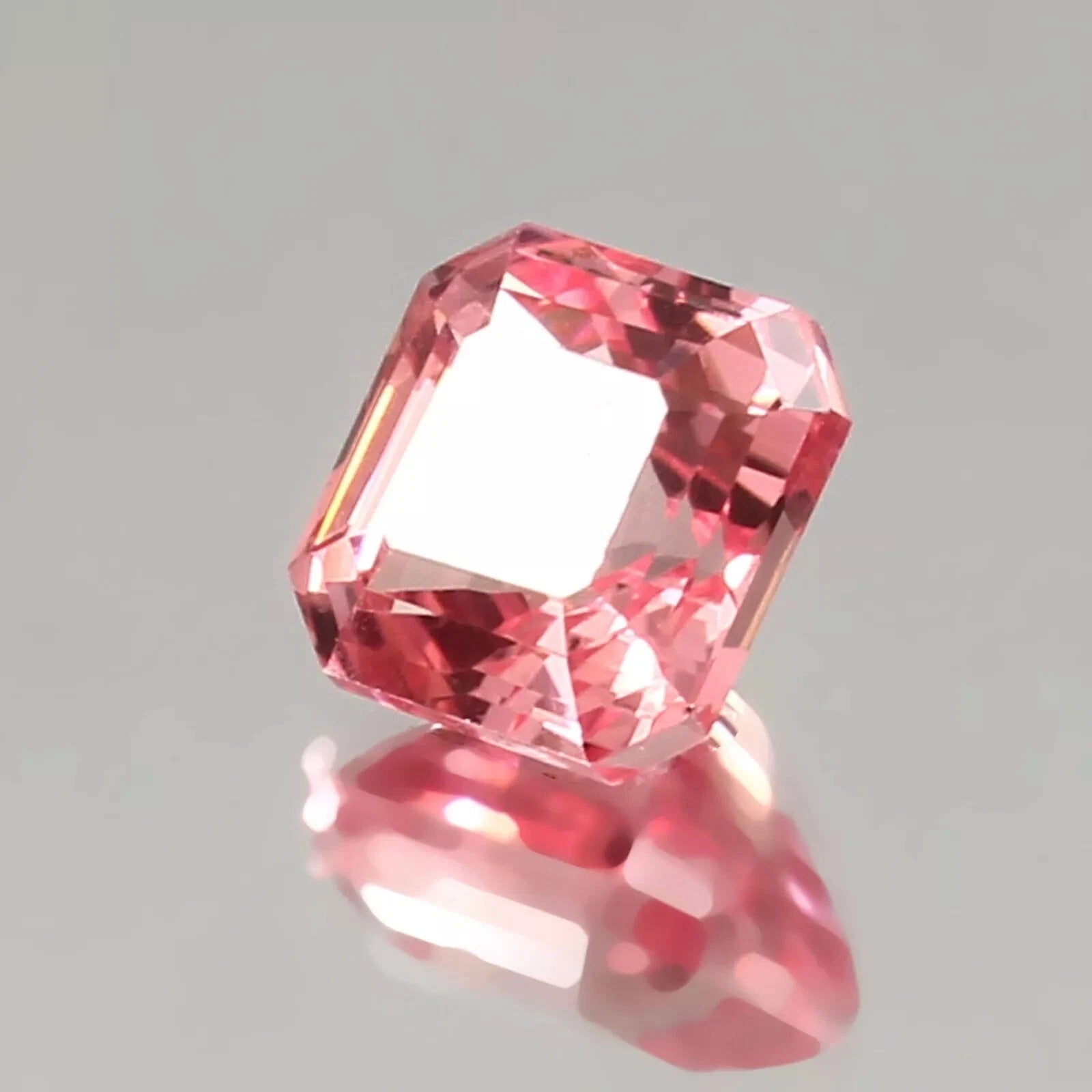 Natural Padparadscha Sapphire gemstone on a gray background