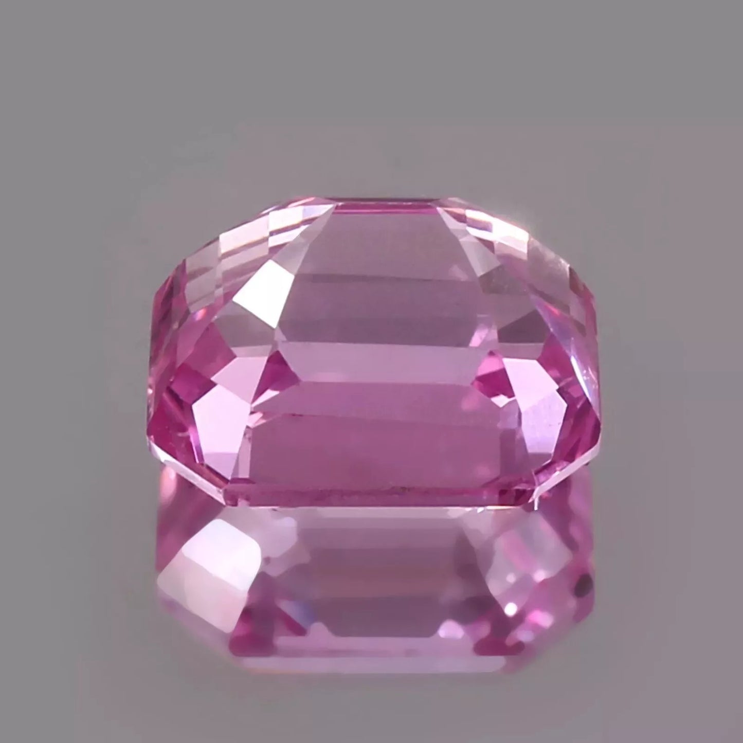 Pink Padparadscha Sapphire gemstone on a gray background