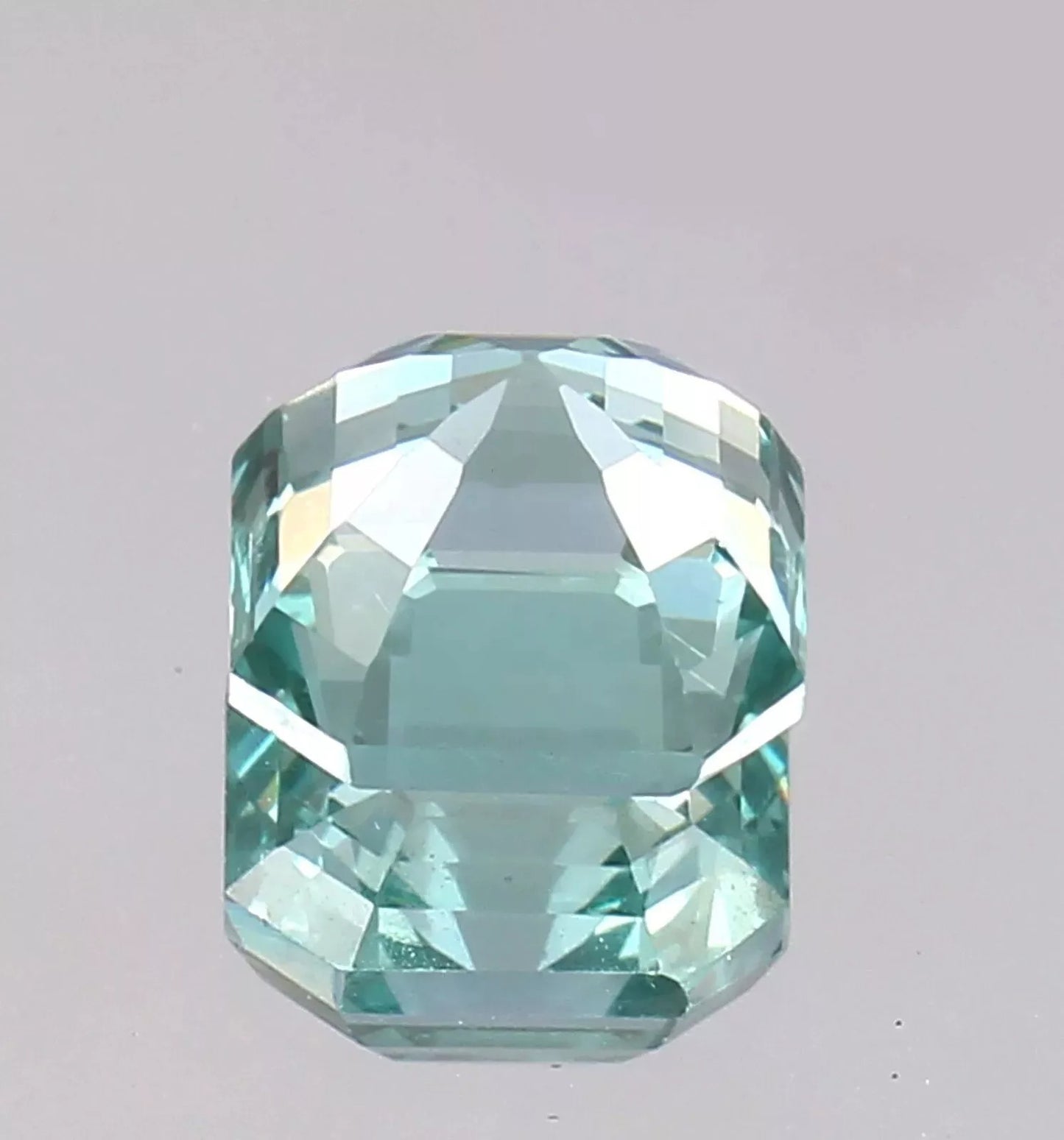 Faceted Green Paraiba Tourmaline gemstone on a gray background