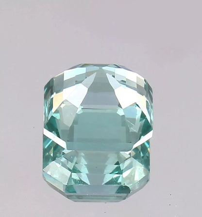 Faceted Green Paraiba Tourmaline gemstone on a gray background