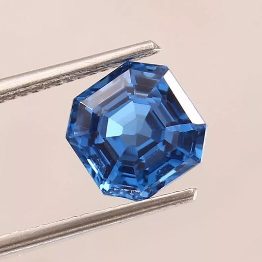 Blue Indicolite Tourmaline gemstone held by tweezers on a beige background