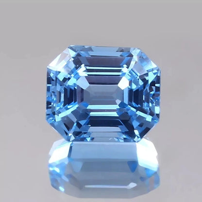 Faceted blue sapphire gemstone on a gray background